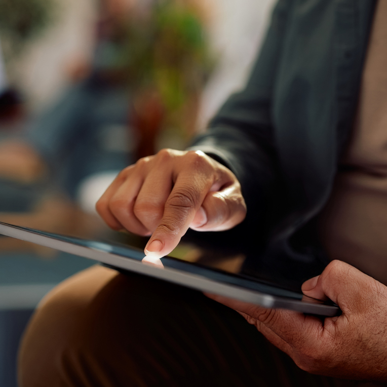 Close up of a person tapping the screen of a tablet.